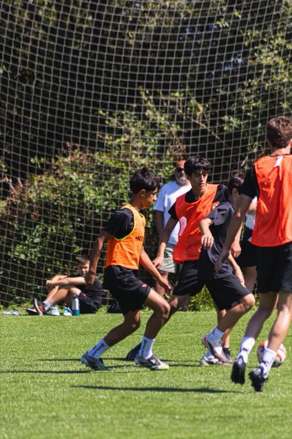 Jugadores con petos naranjas en una situación de juego en el campo de la academia