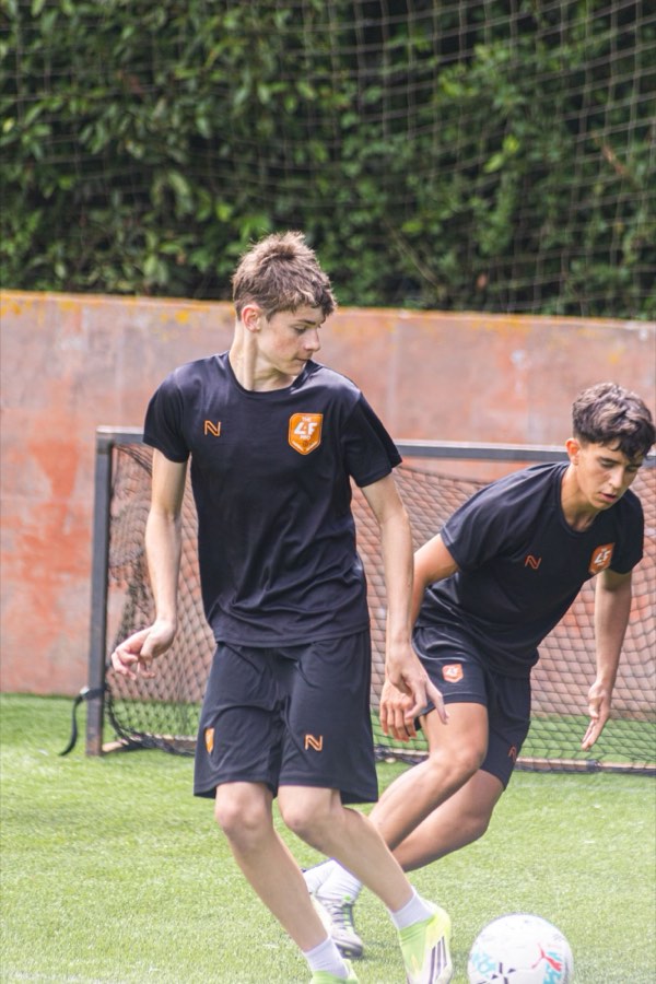 Dos jugadores con la equipación de THEL4FPRO trabajando la técnica en el campo de la academia