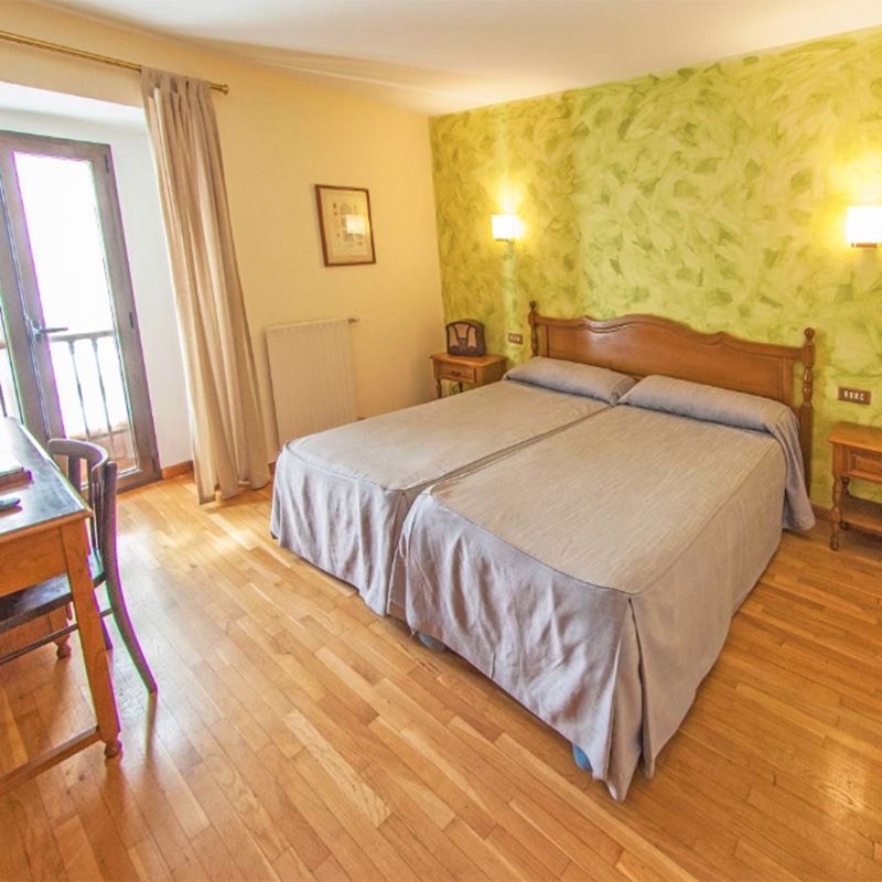 Habitación twin del hotel con dos camas individuales, escritorio y suelo de madera